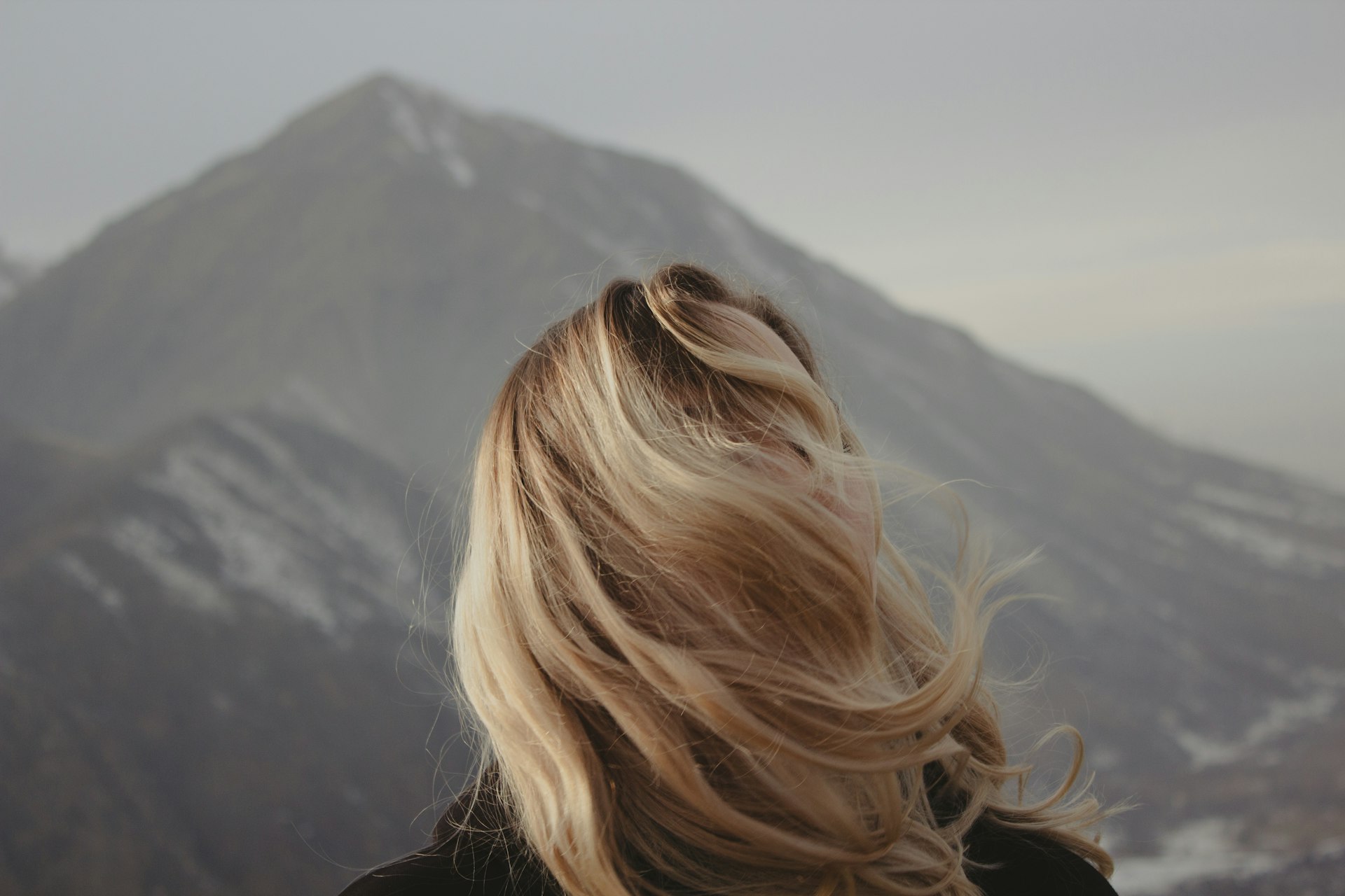 a woman with blonde hair looking at a mountain